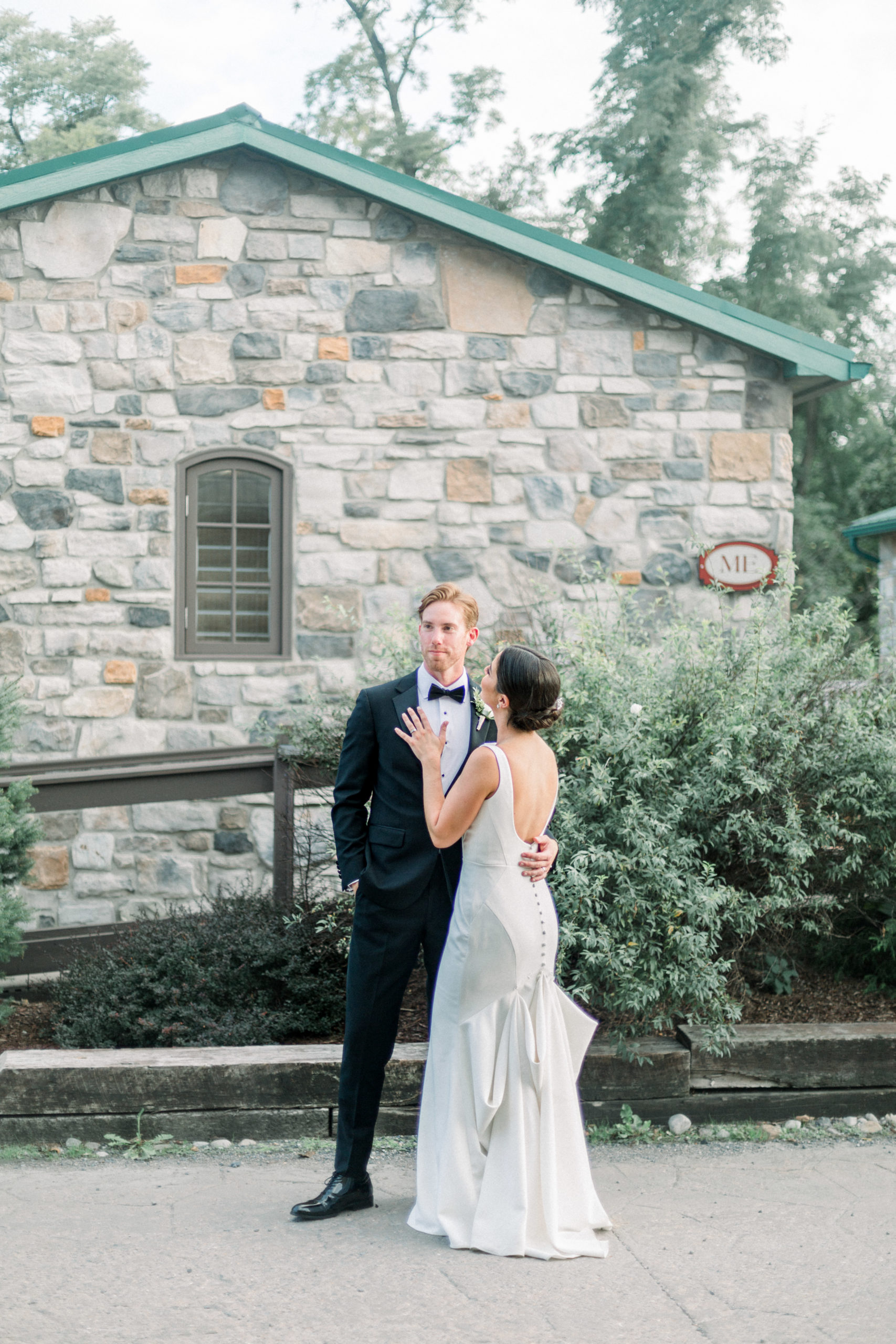 bride and groom embrace each other in front of a stone cottage