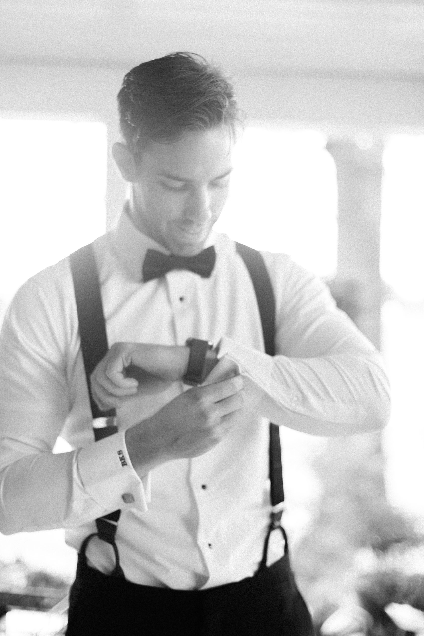 groom getting ready as he puts on his watch and smiles
