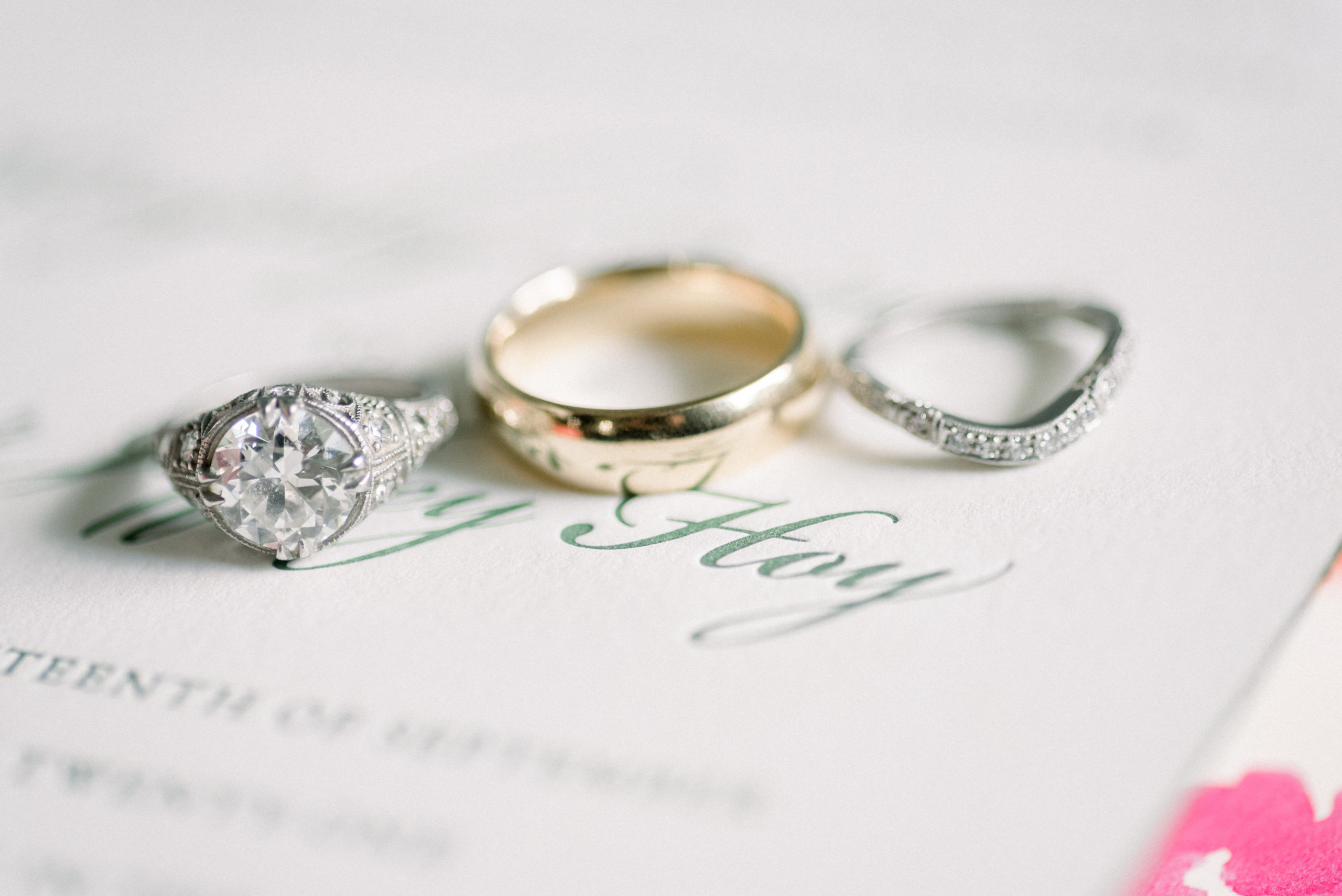 close up shot of engagement ring, weddings bands on wedding invitation
