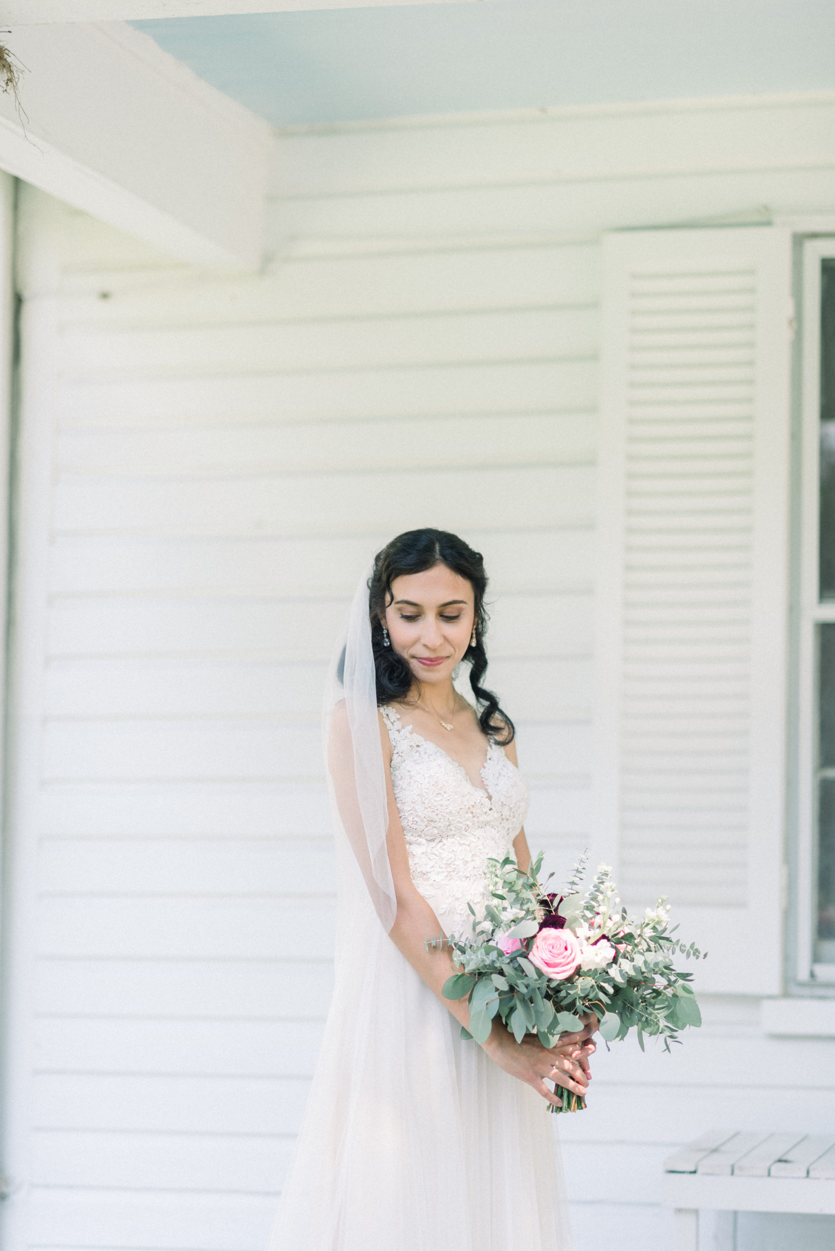 bride looking away holding bouquet of pink florals and eucalyptus 