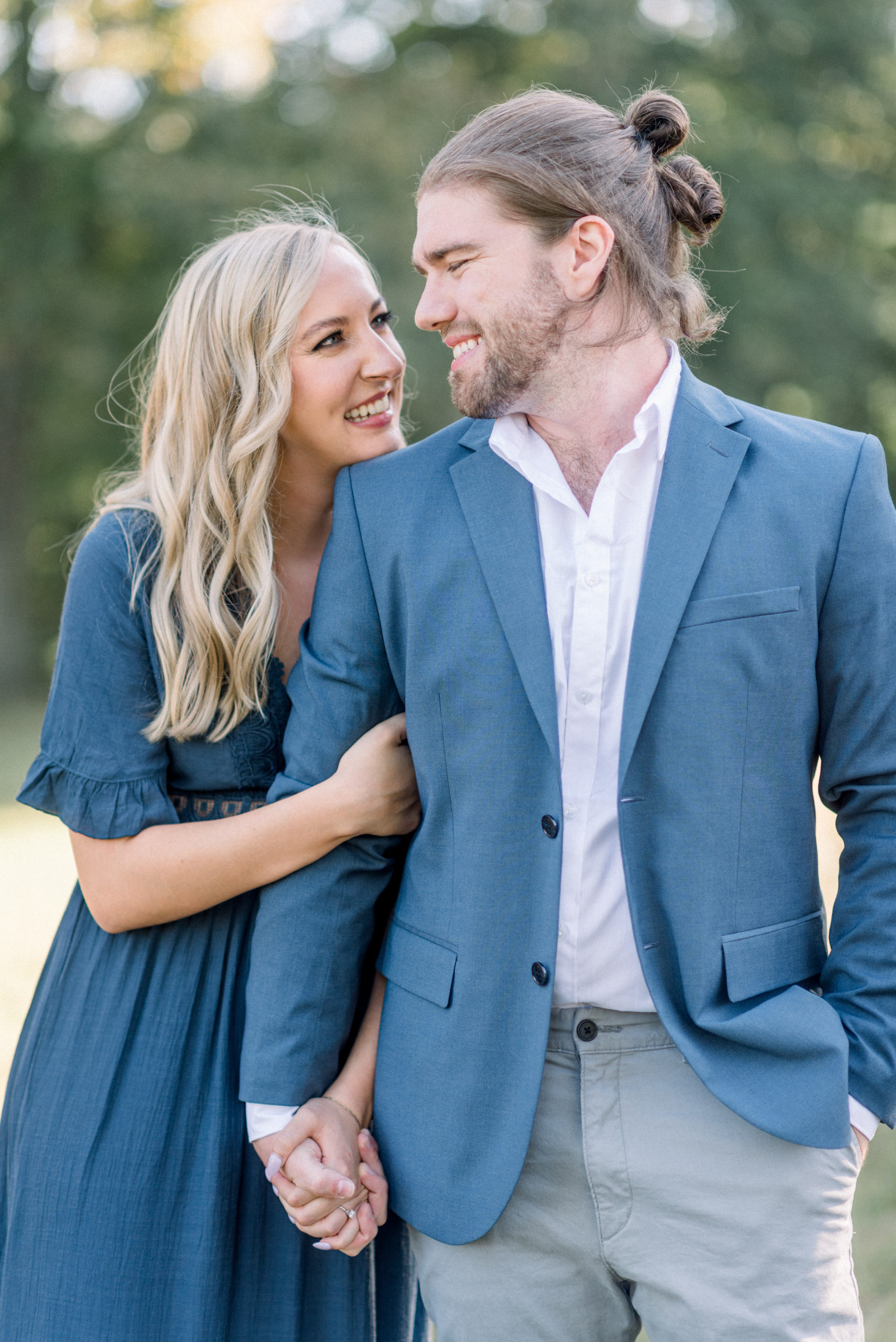 woman holding hands with fiancé smiling during engagement portraits