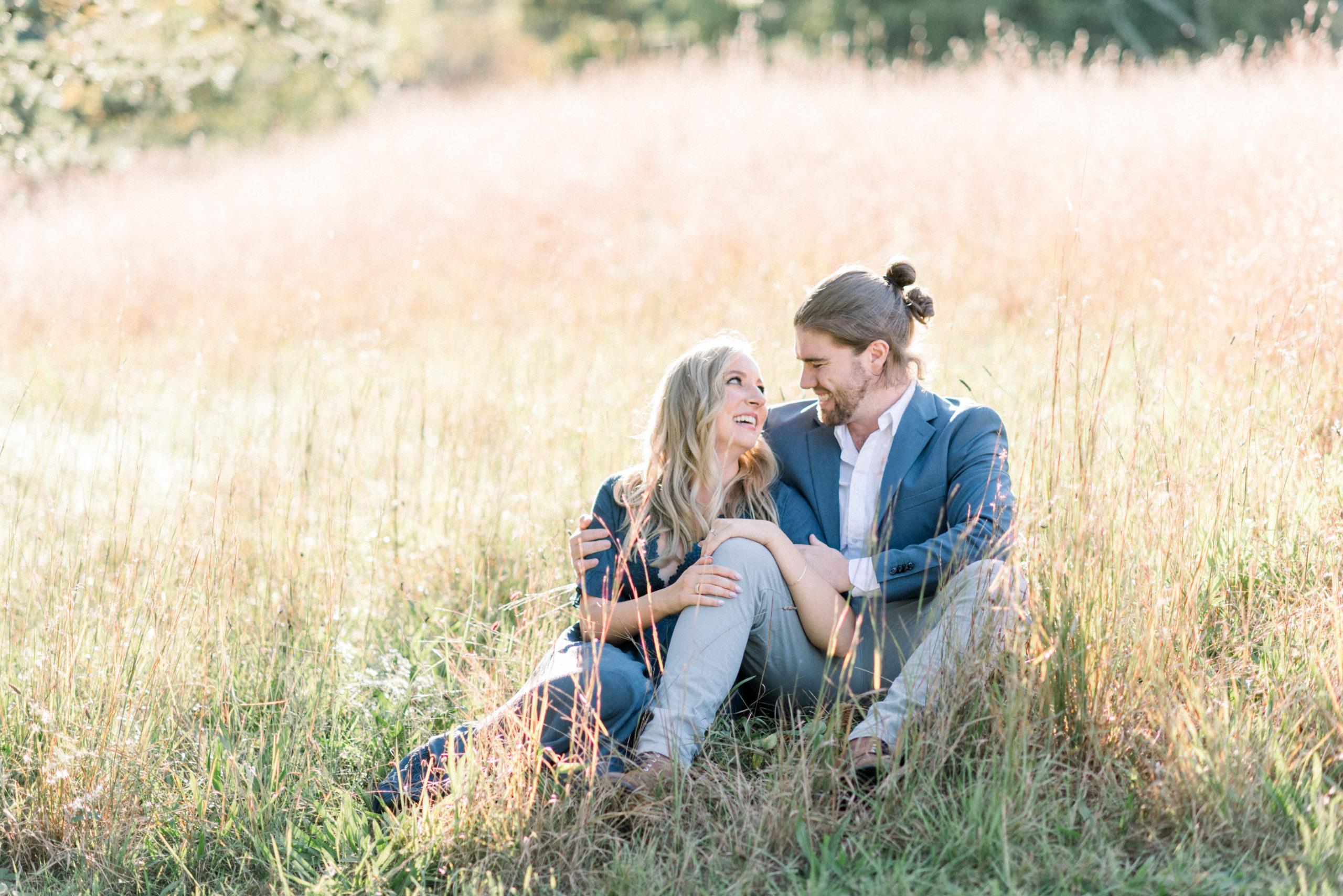man and woman sitting on hill during engagement portraits