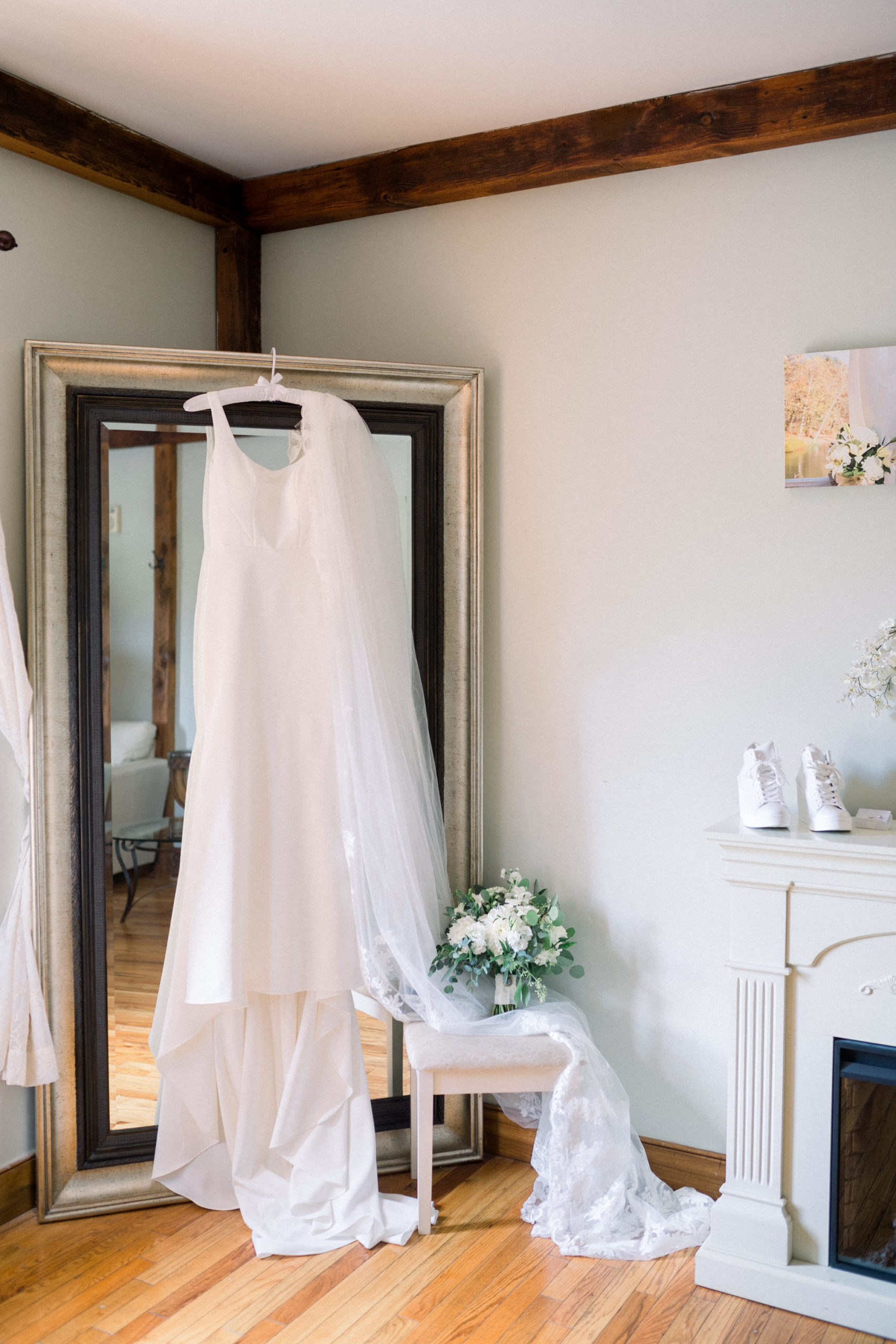 elegatn satin wedding dress hanging on a mirror in a bridal suite