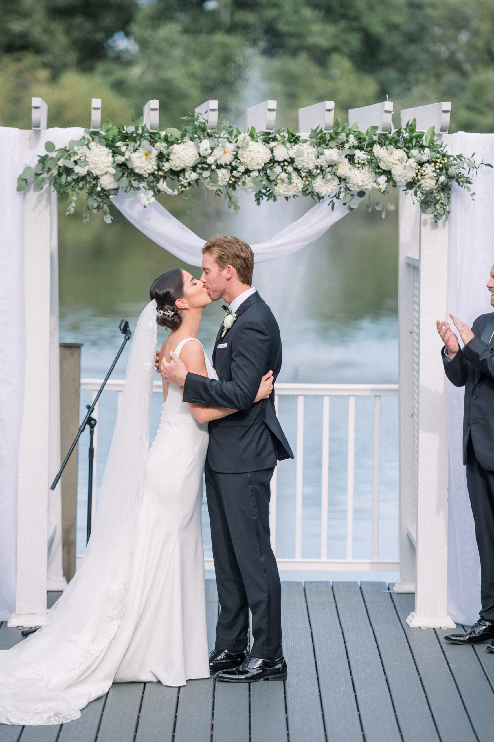 bride and groom kissing after their wedding ceremony outside on a lake