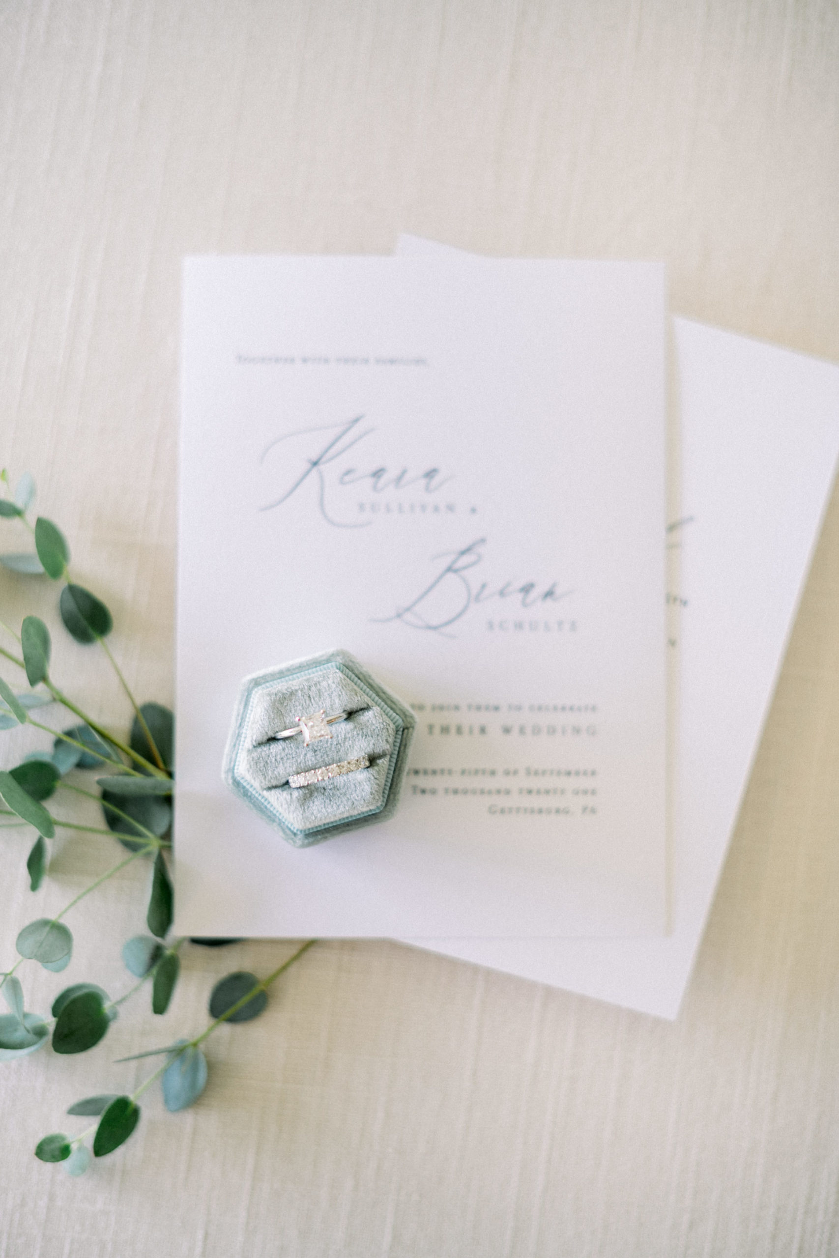 wedding invitation and wedding rings next to greenery for timeless wedding