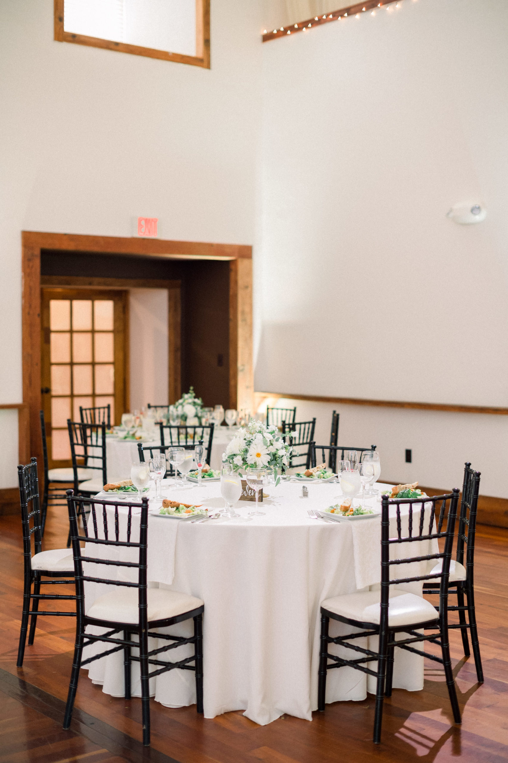 circle table with white table cloth and elegant centerpieces and black chairs