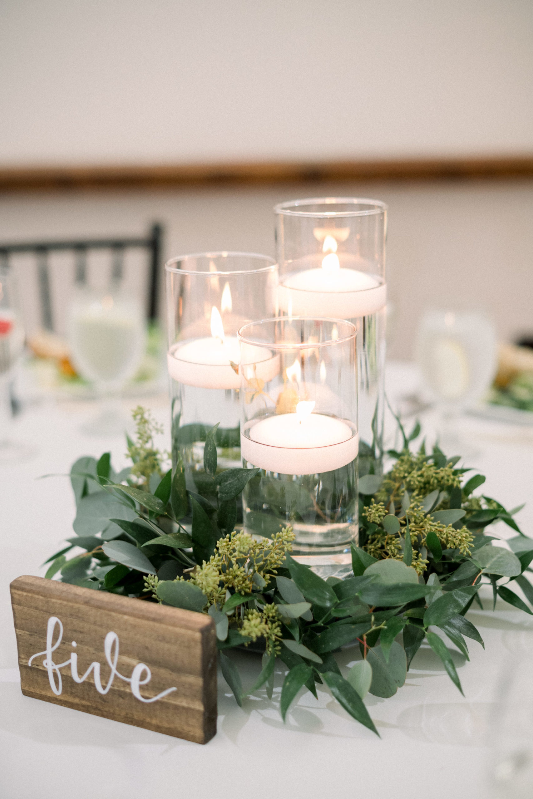 centerpiece for wedding tables with tiered candles surrounded by greenery