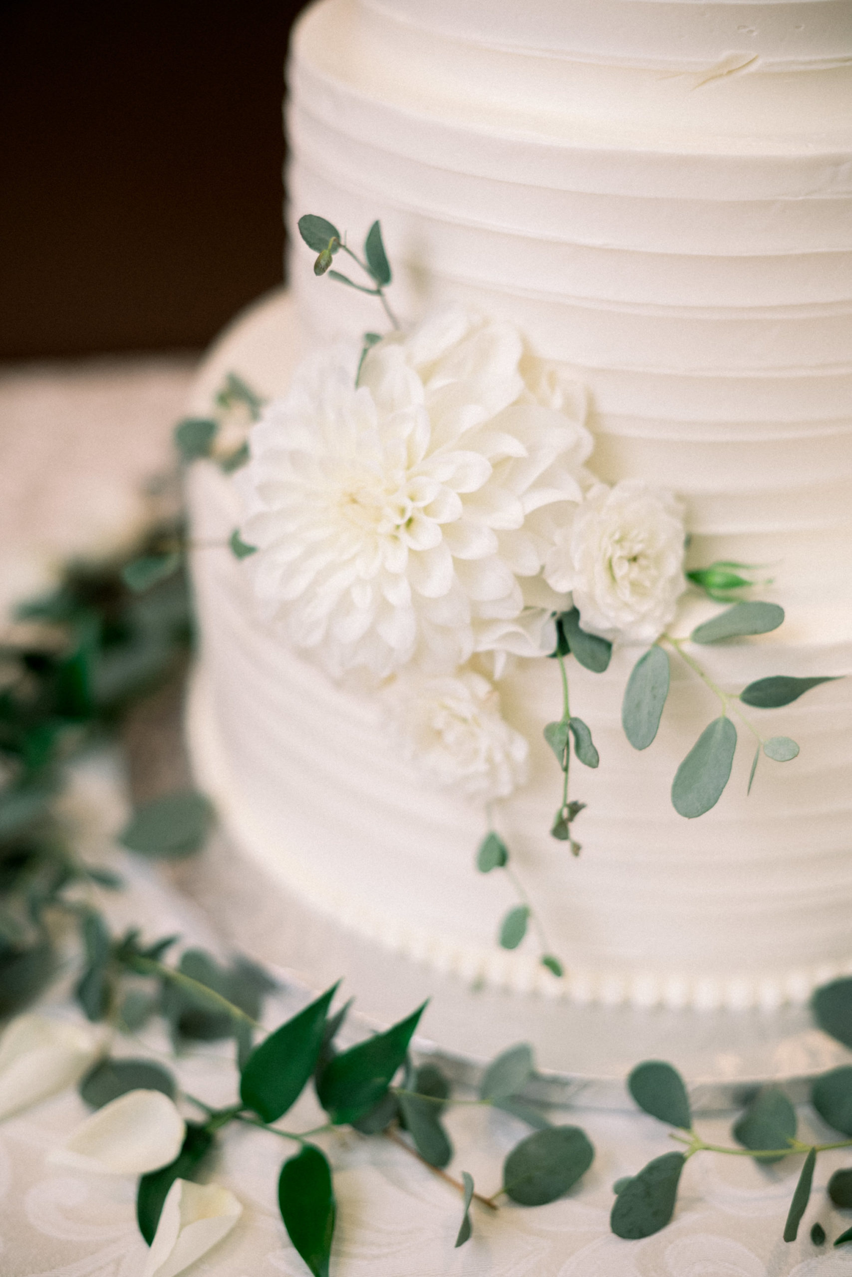 detail shot of white wedding cake with white florals on the base of the wedding cake