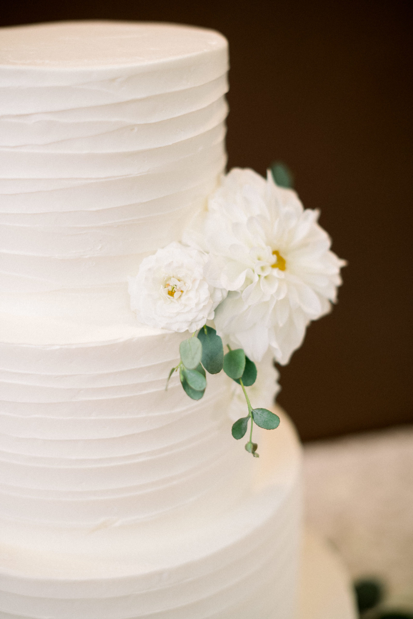 white florals on white wedding cake and little green leaves
