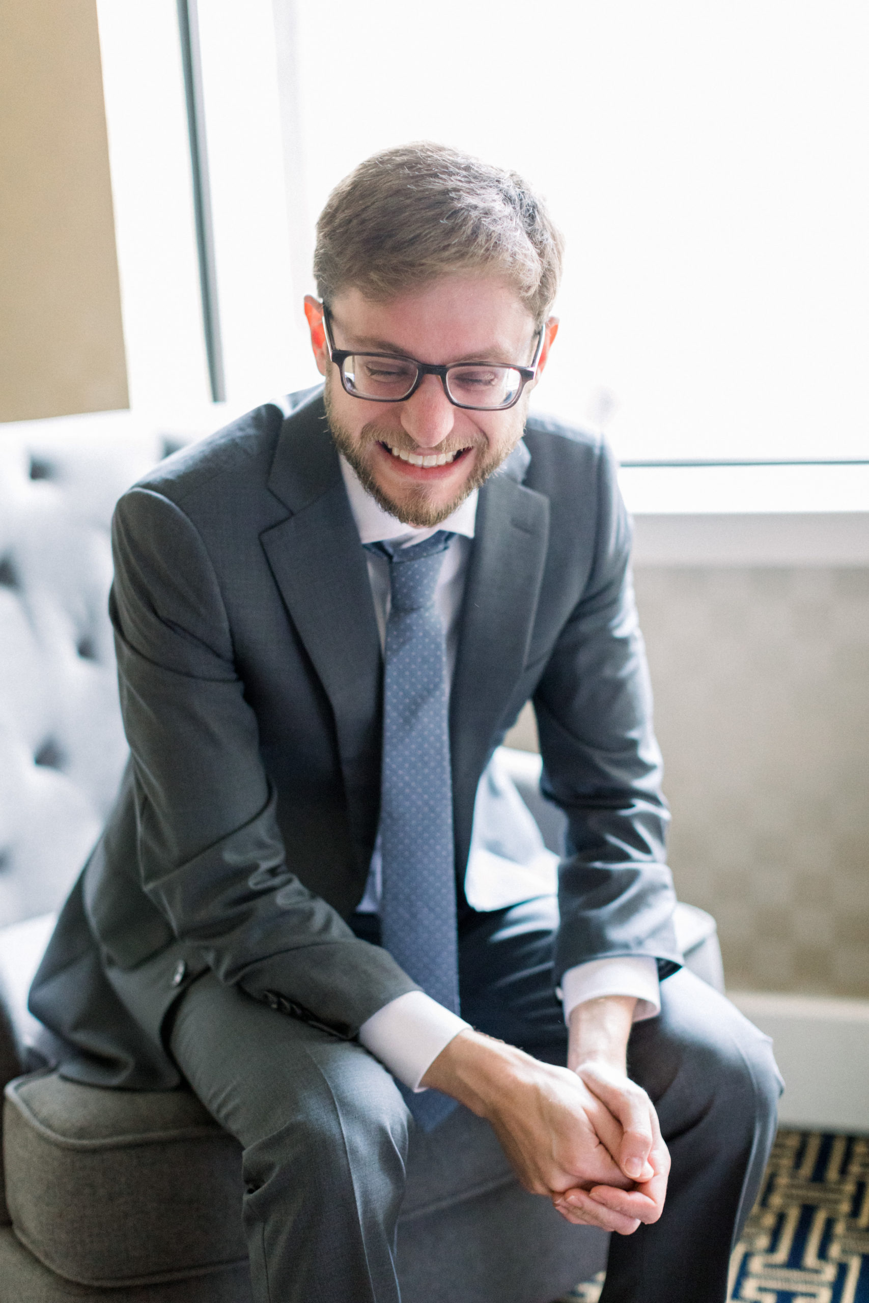 groom smiling wearing gray suit and glasses