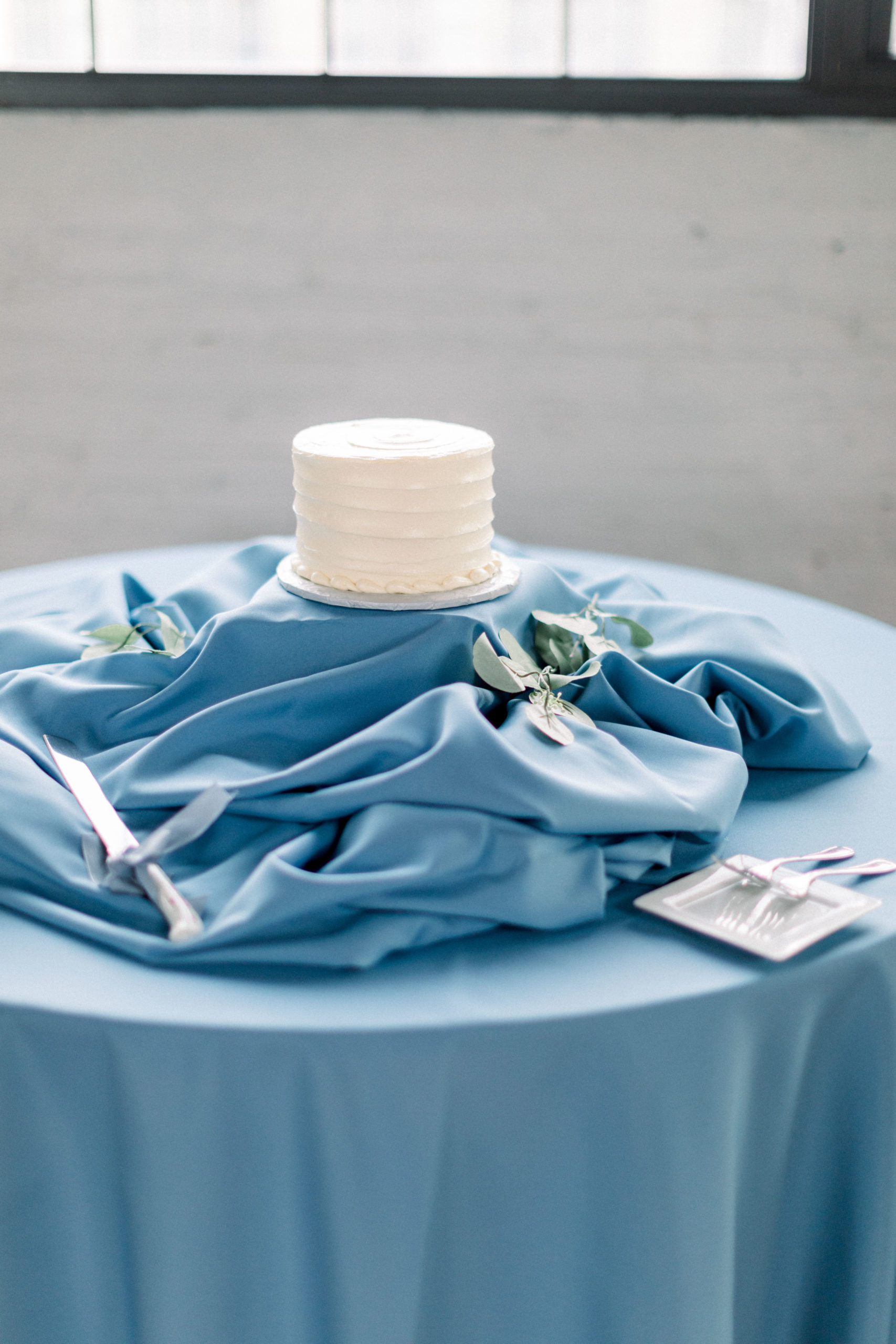blue tablecloth with white cake sitting on top for cake cutting