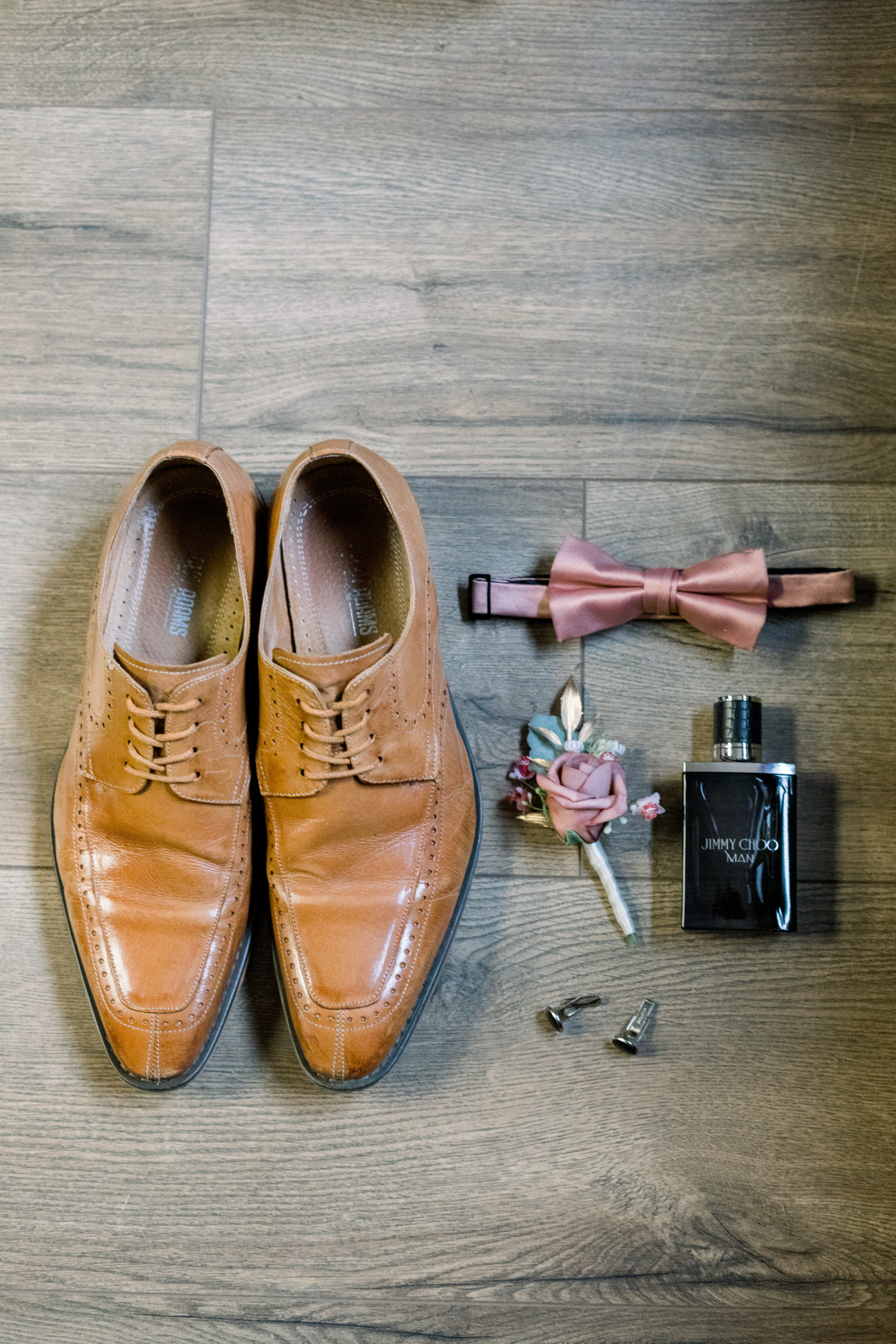 close up of groom's details, brown shoes, cologne, boutonnière