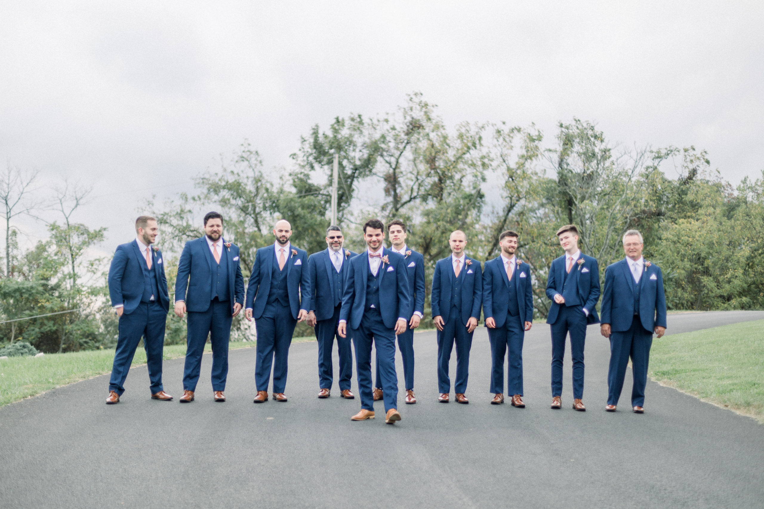 groom standing with groomsmen all wearing navy suits and pink ties before stunning lodges at gettysburg wedding ceremony