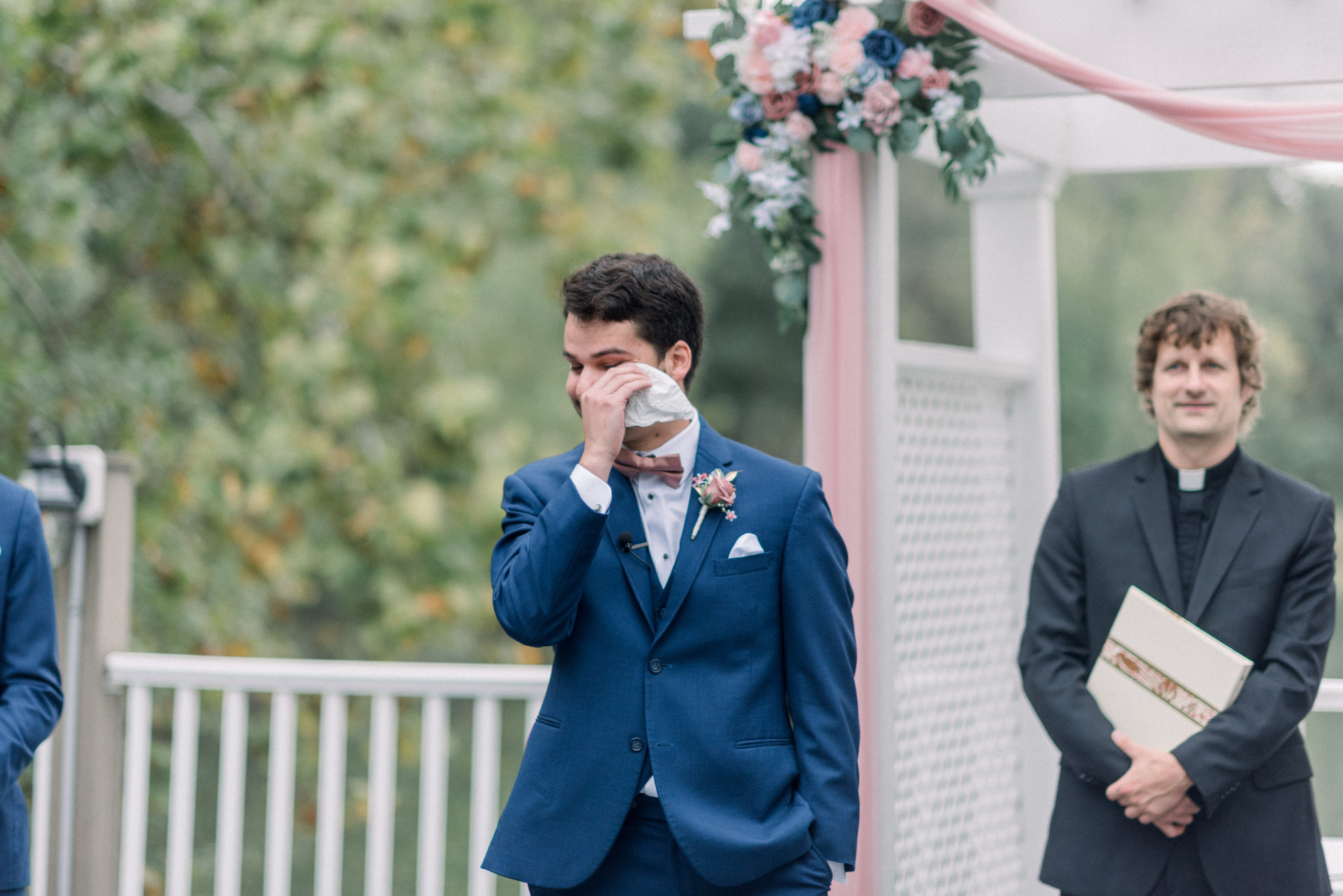 groom standing at alter crying while bride walks down aisle