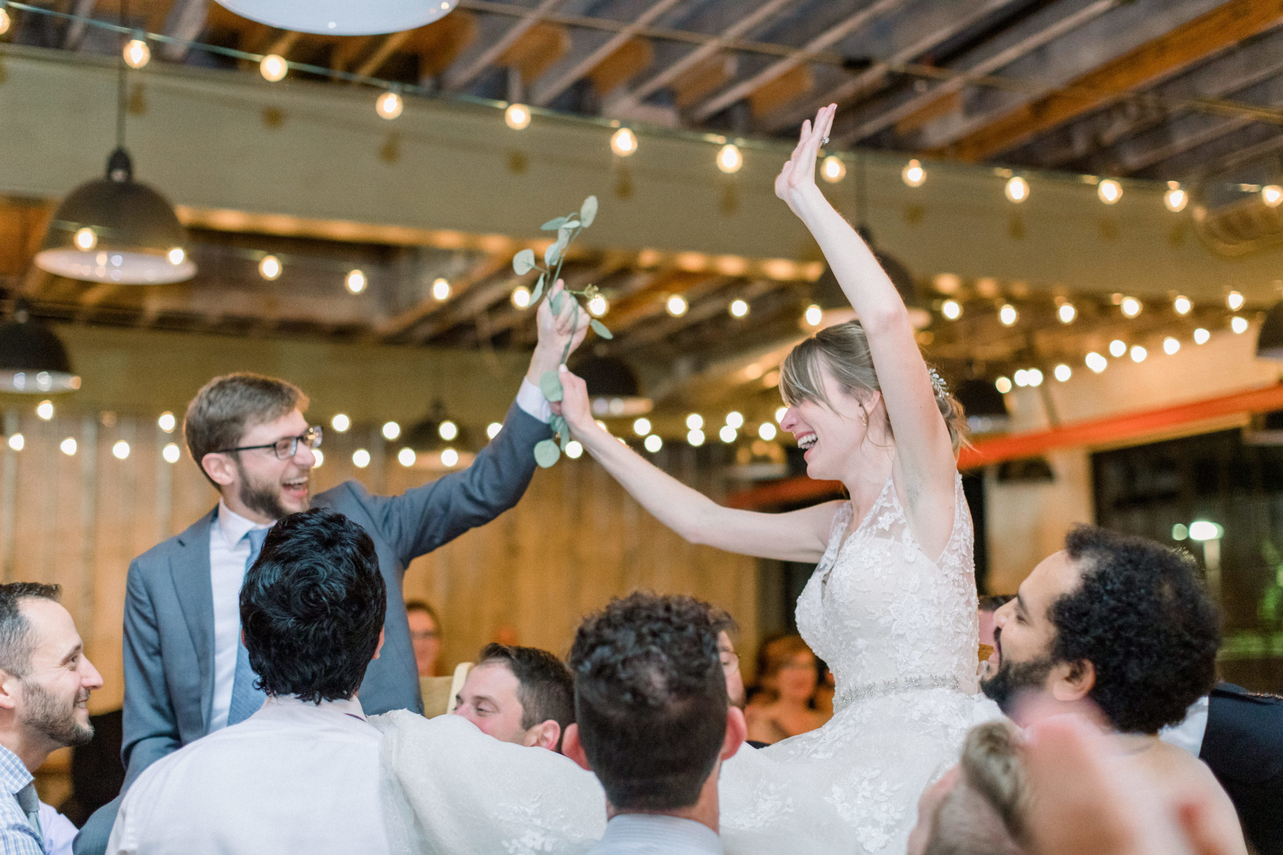 bride and groom being lifted up on chairs during wedding reception