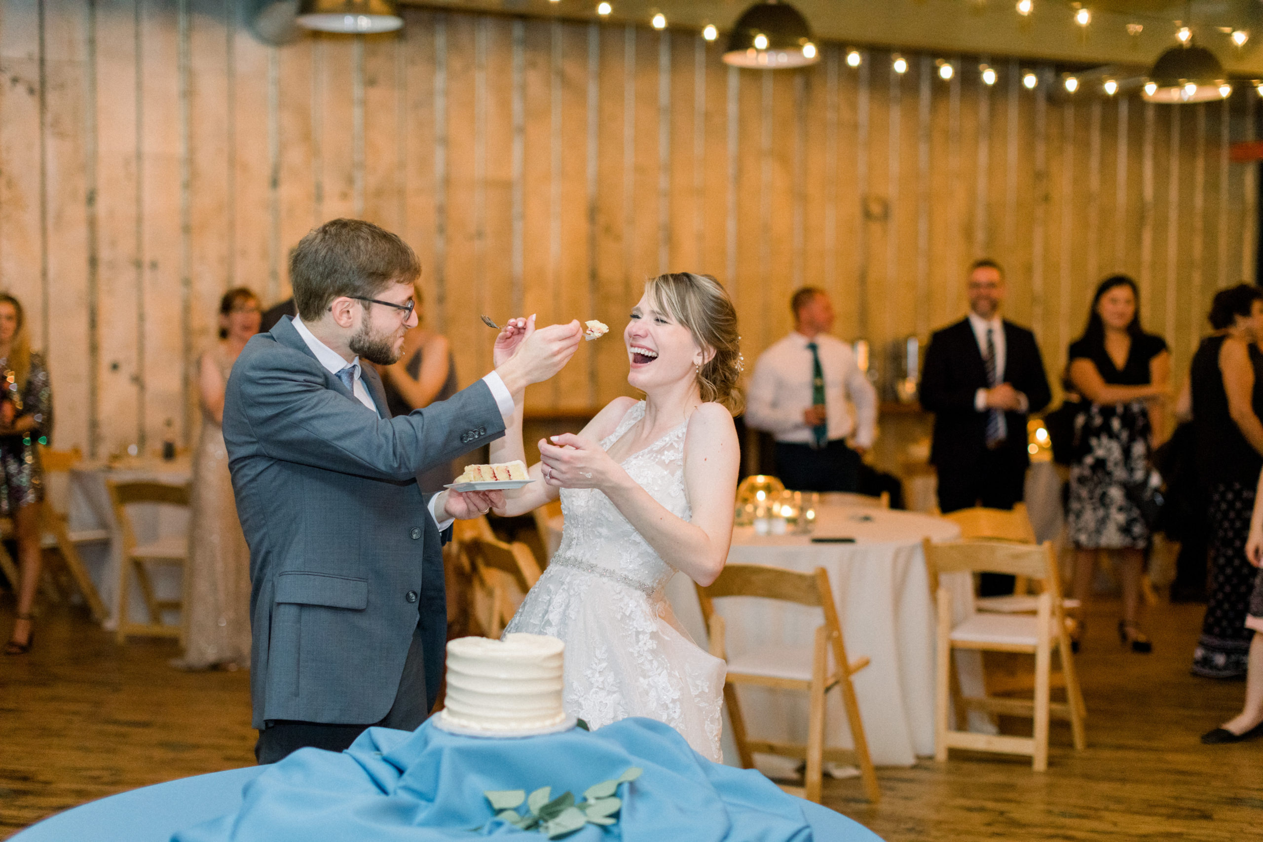 bride laughing as groom feeds her wedding cake at elegantly Modern Accelerator Baltimore Wedding