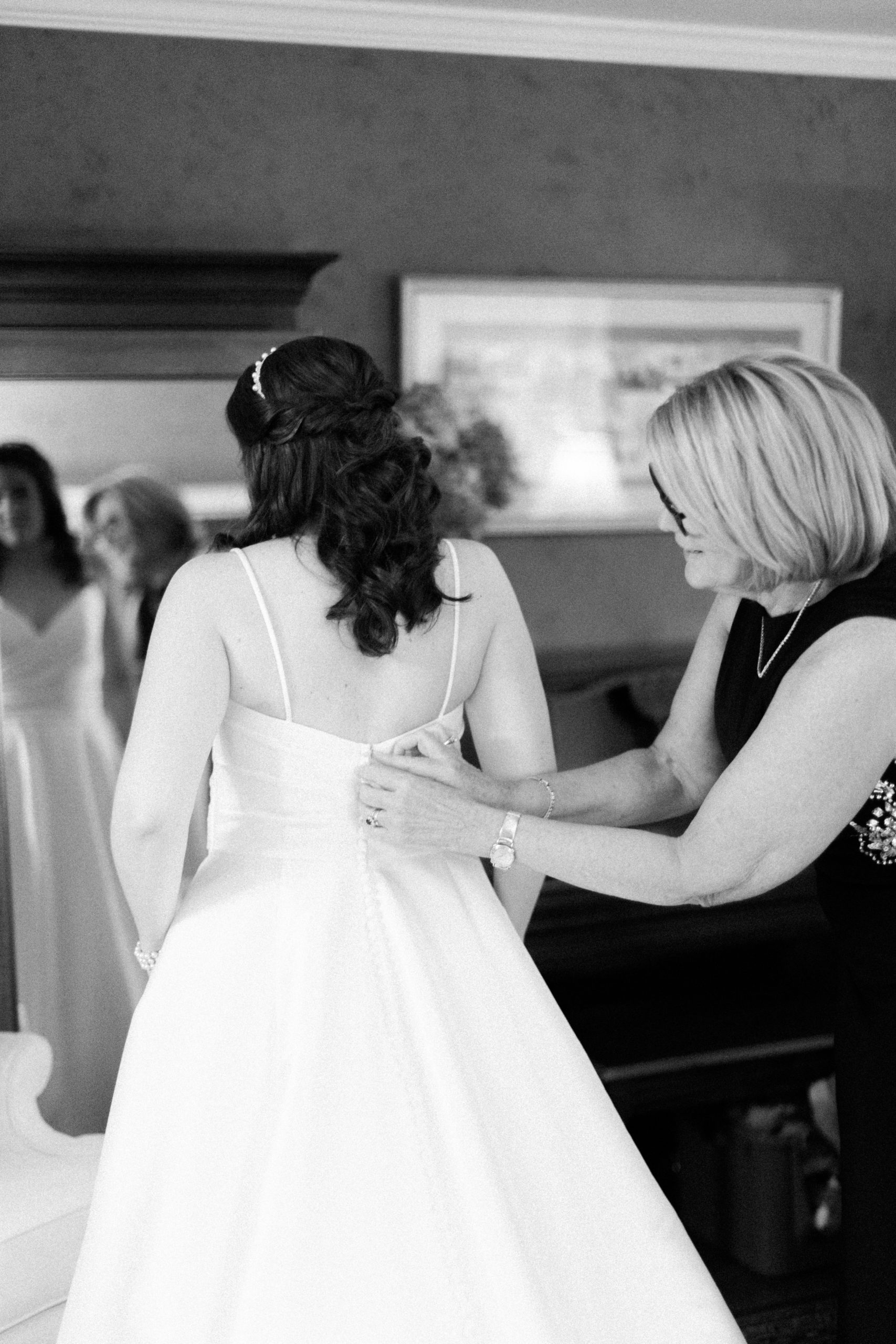 bride getting buttoned into dress