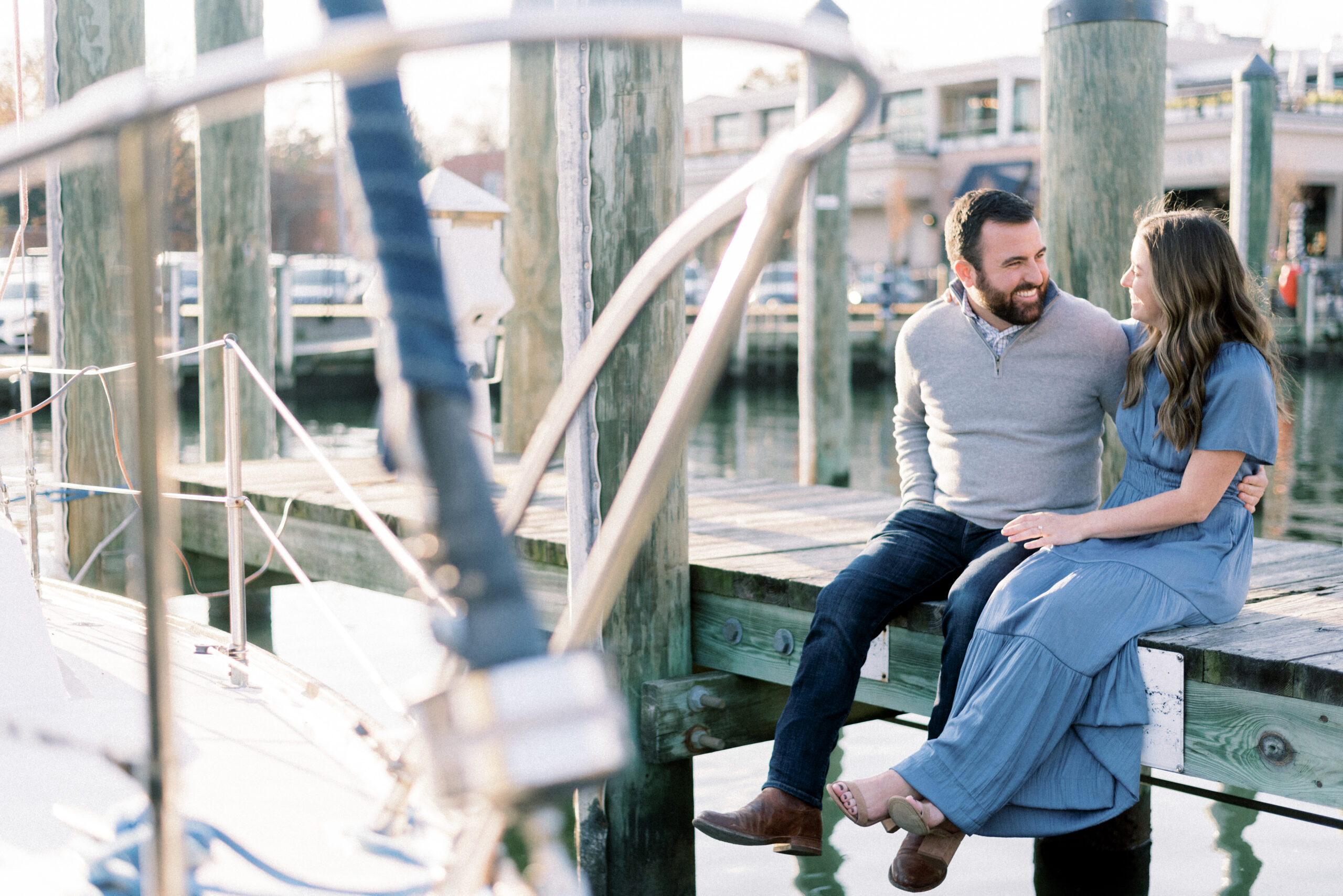 Maryland wedding photographer captures couple sitting on dock during downtown Annapolis Engagement portraits
