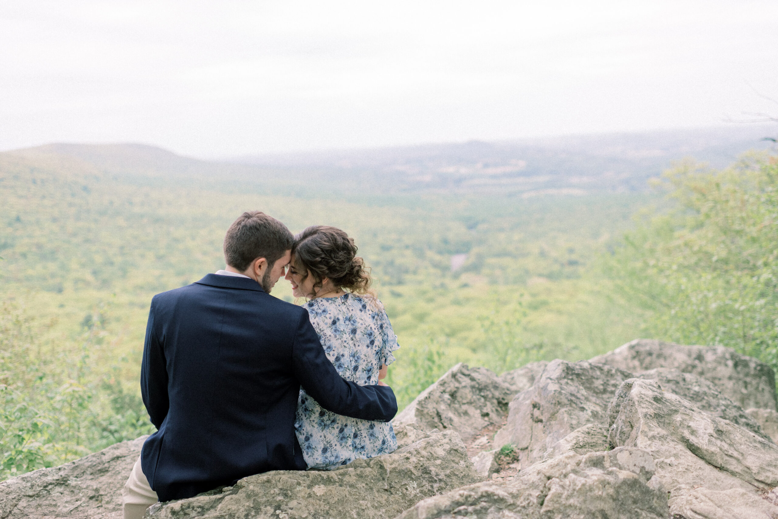 Maryland wedding photographer captures couple sitting on Hawk Mountain during engagement portraits
