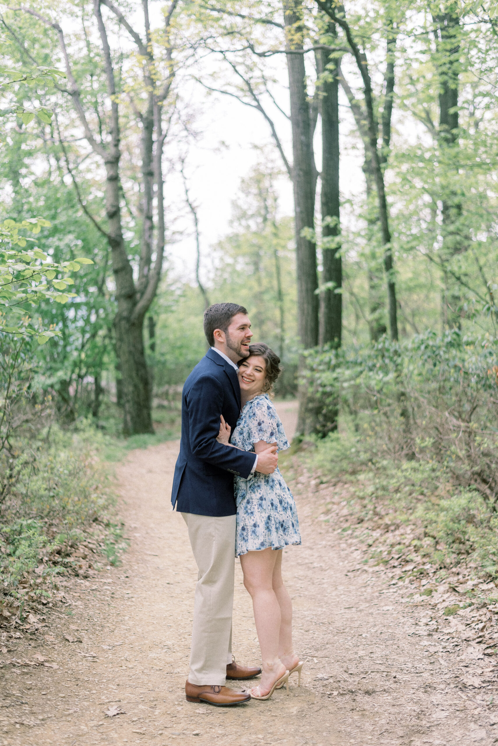 Maryland wedding photographer captures couple hugging in forest during engagement portraits