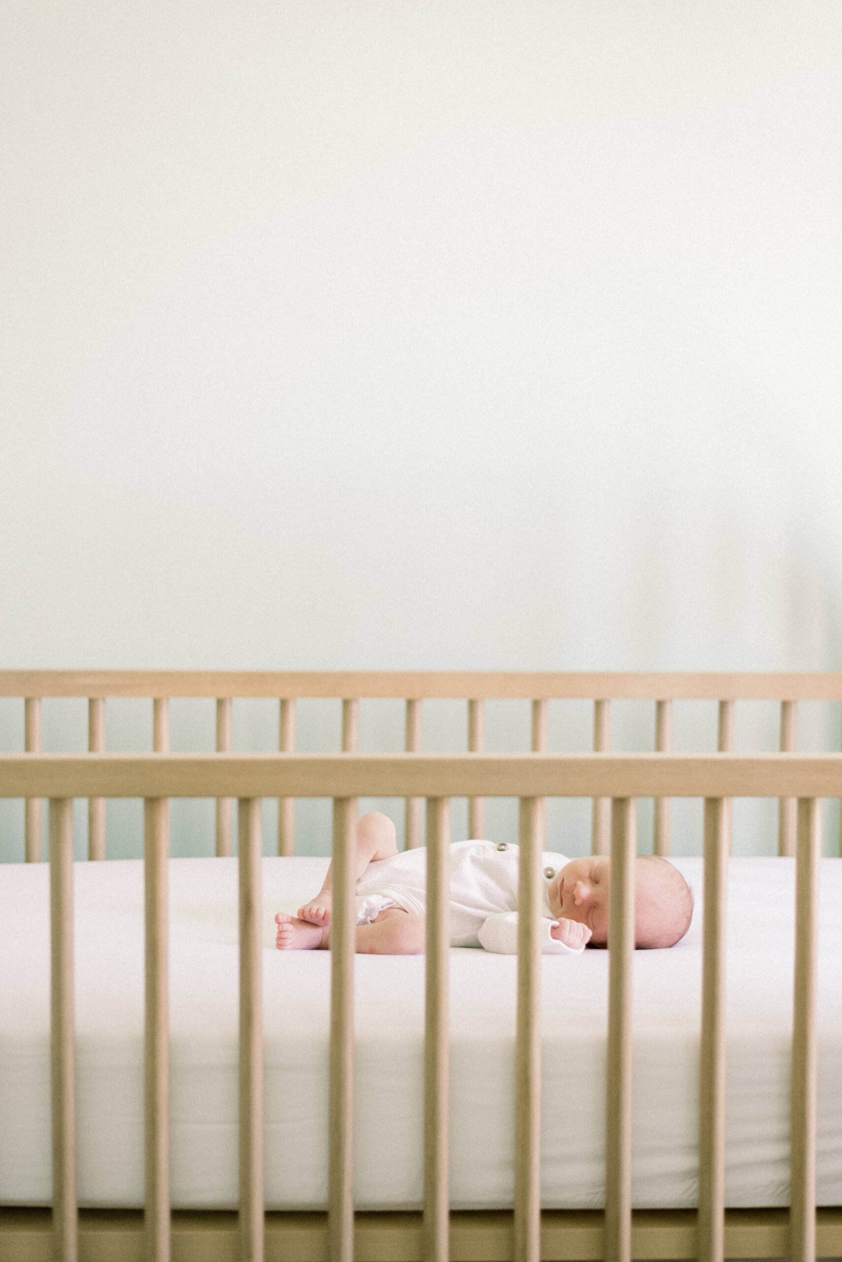 Pennsylvania photographer captures newborn baby in white onesie laying in crib