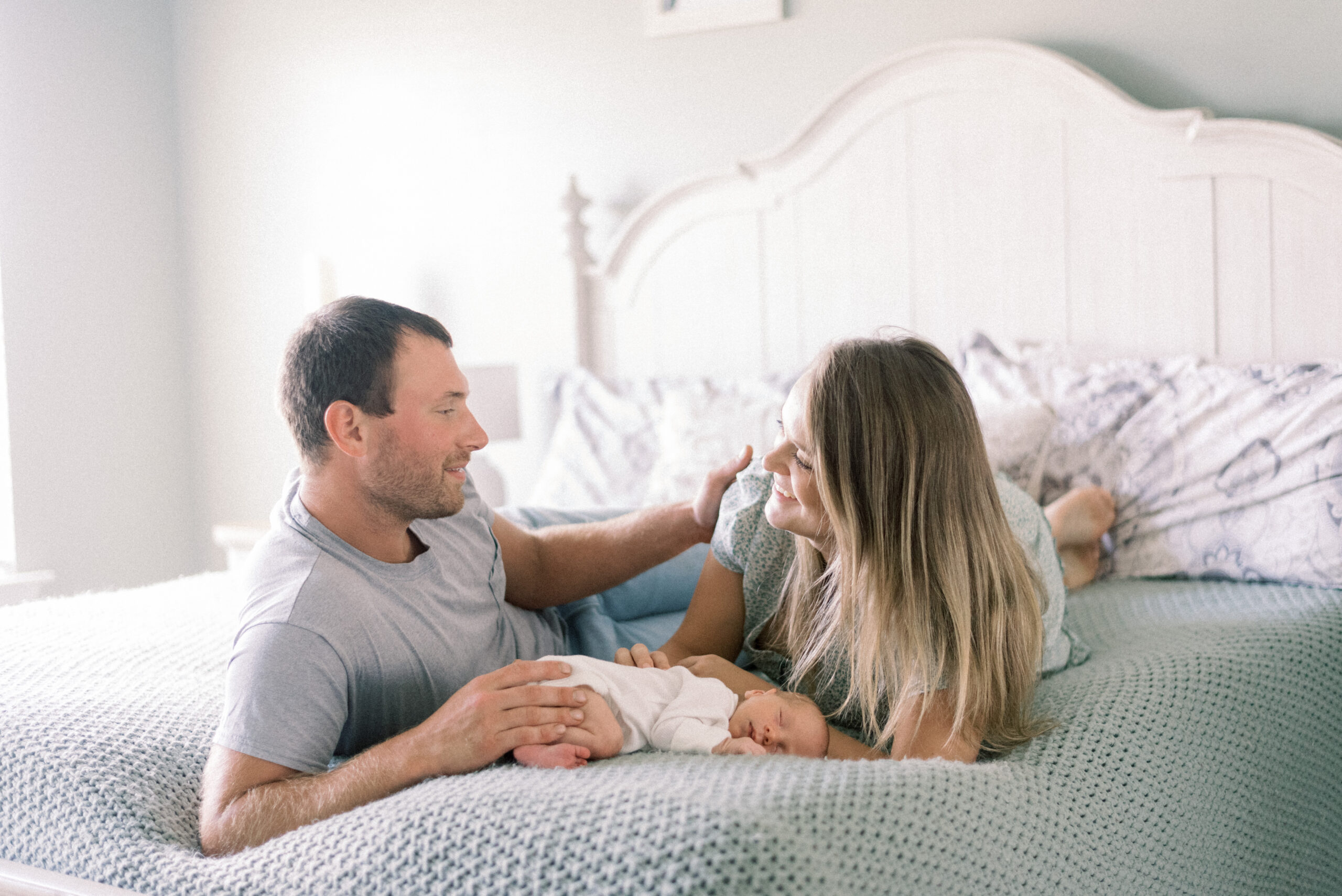 Pennsylvania photographer captures couple laying in bed talking while baby sleeps