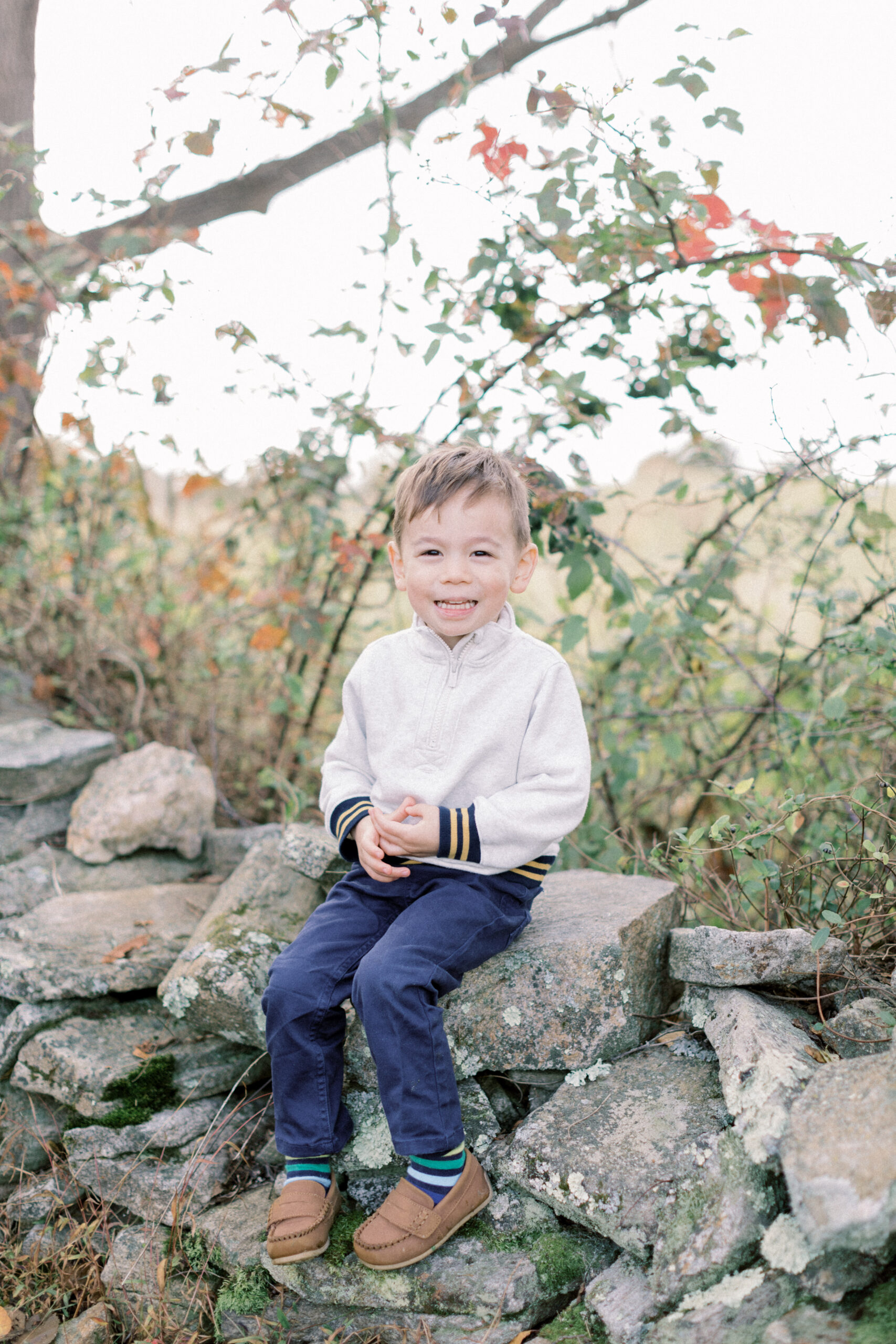 Maryland photographer captures young boy smiling at camera while sitting on wall