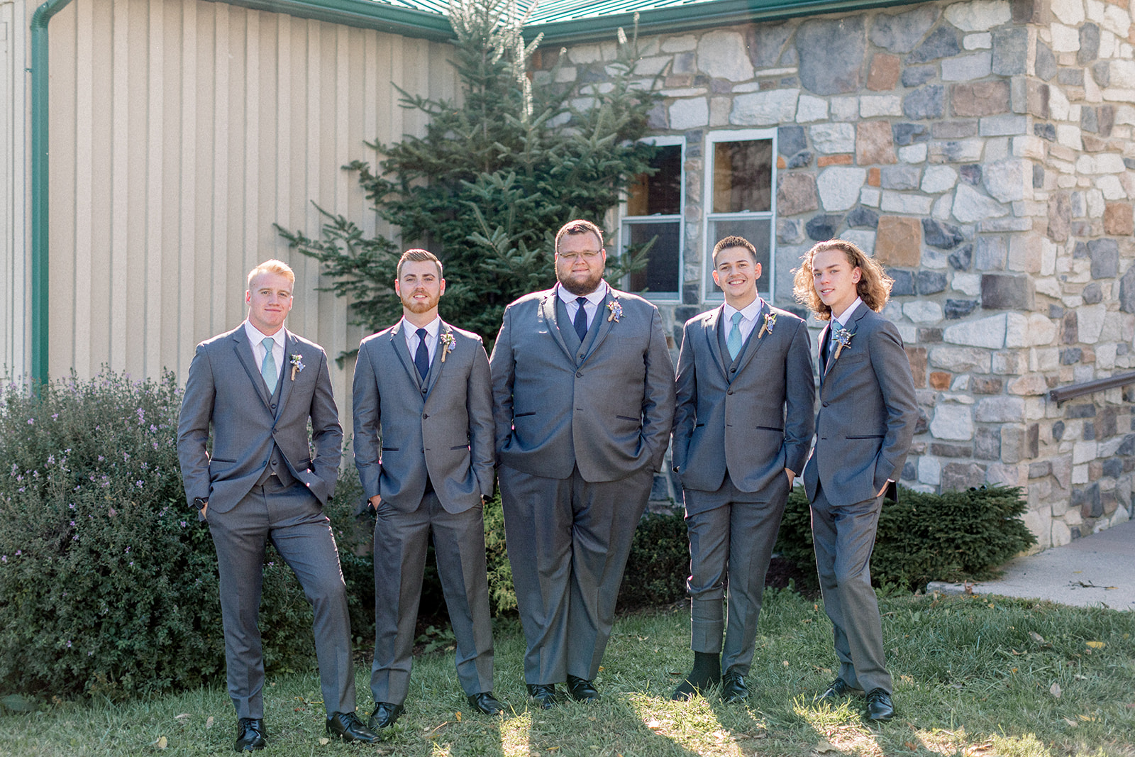 Pennsylvania wedding photographer captures groom standing with groomsmen wearing gray suits before wedding at Lodges of Gettysburg