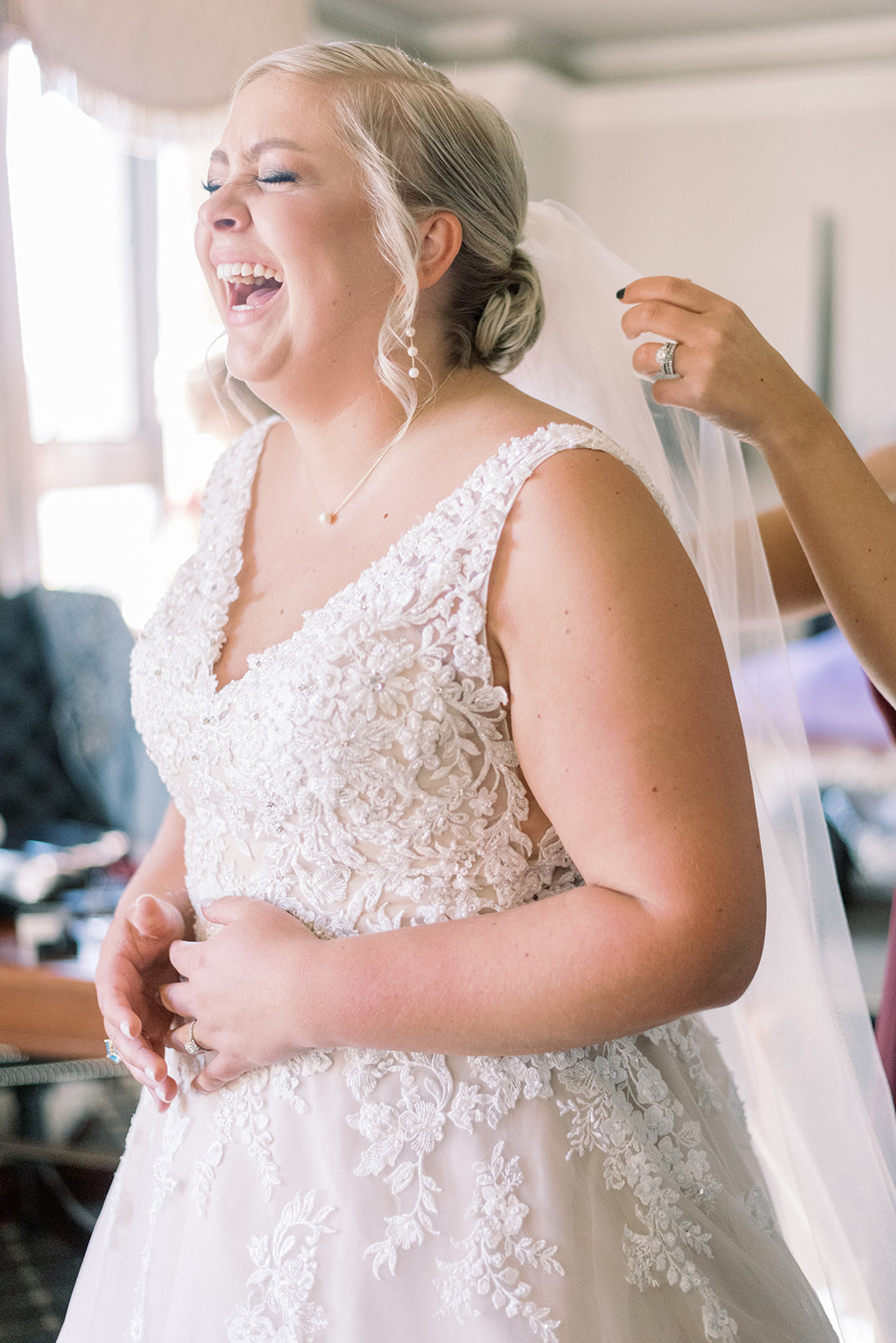 Pennsylvania wedding photographer captures bride laughing while putting veil on