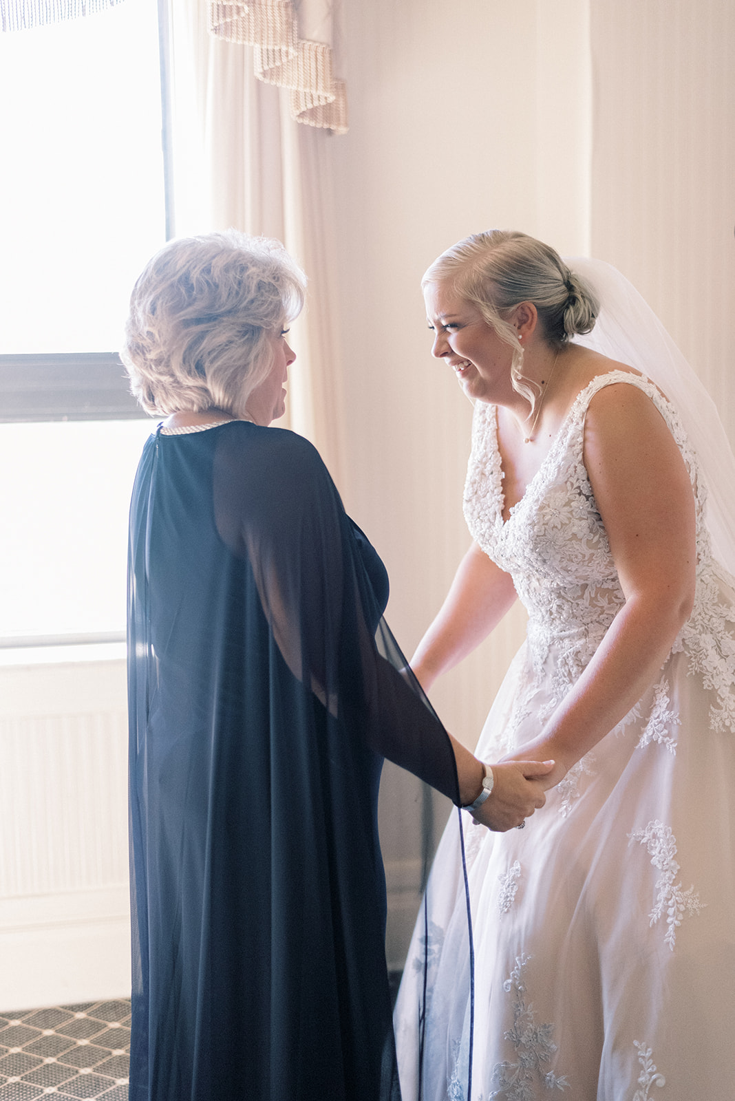 Pennsylvania wedding photographer captures bride holding mother's hands and smiling