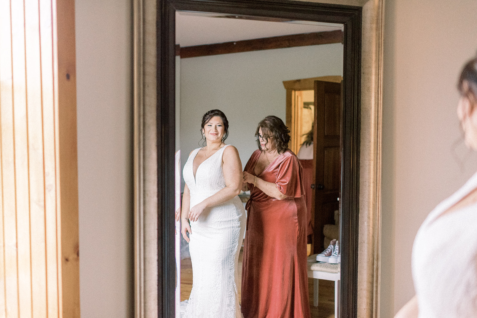 Pennsylvania wedding photographer captures bride smiling while mother helps her into dress