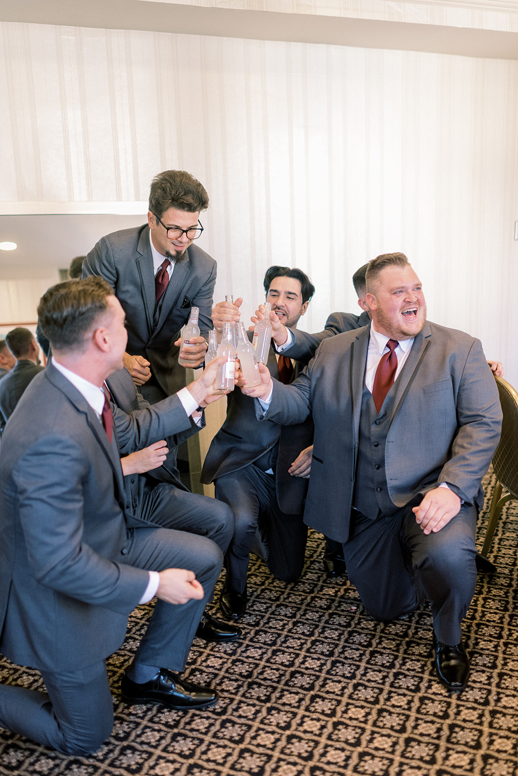 Pennsylvania wedding photographer captures groomsmen kneeling and toasting drinks