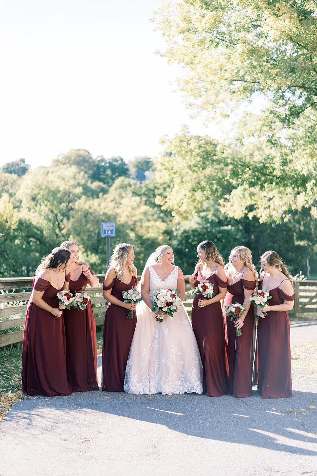 Pennsylvania wedding photographer captures bride laughing with bridesmaids wearing burgundy dresses