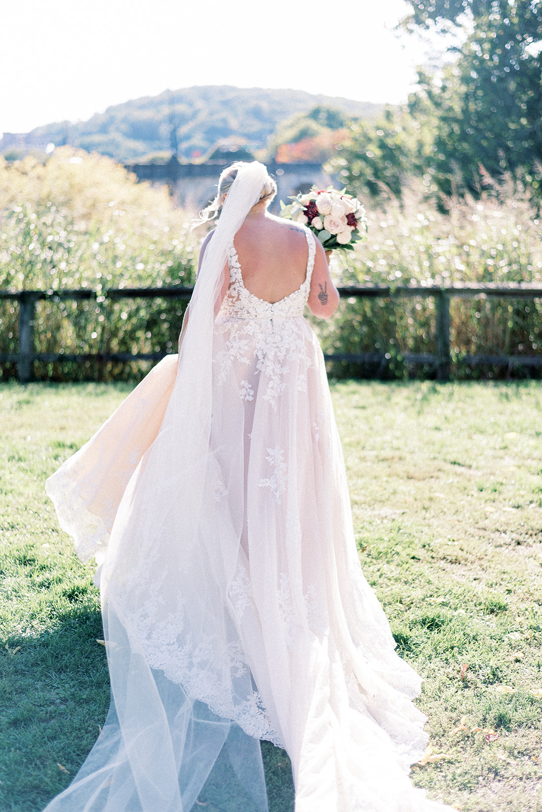 Pennsylvania wedding photographer captures bride lifting dress and bouquet as she walks
