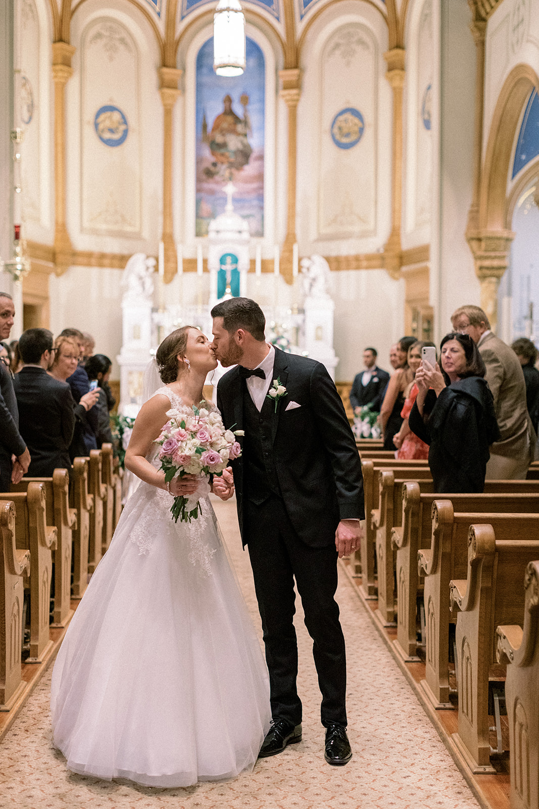 Pennsylvania wedding photographer captures bride and groom walking out of ceremony kissing as newly married couple